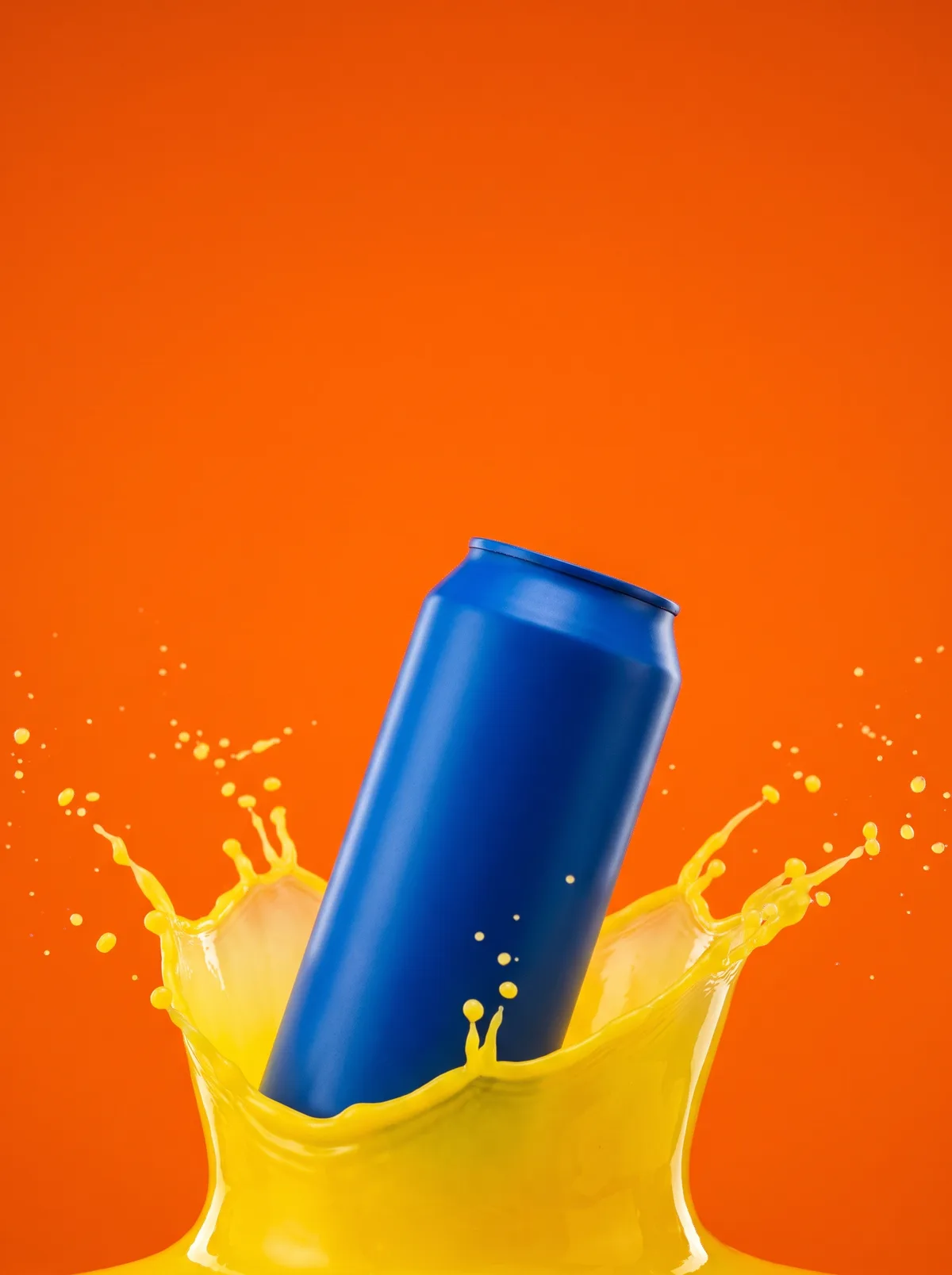 A product shot of a matte blue beverage can crowned in a splash of yellow liquid against a solid orange background.